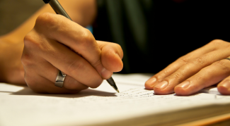 A hand writing with a pen in a journal.