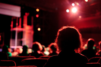 Audience members view a stage production