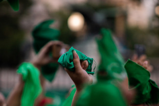 Women's hands holding up green flags, a symbol of pro-choice in Latin America