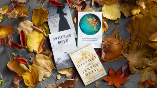 The Books "Switching Sides," "The Secret History of the Jersey Devil," "Bizarre Bioethics," and "Dead Women Talking" in a pile of autumn leaves.