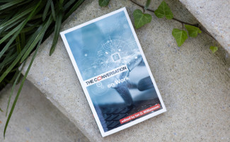 The book cover of The Conversation on Work, which features a robot's hand, resting on stone steps.