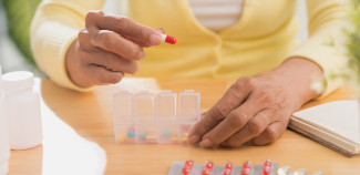 women putting pills in pill box