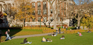 University grounds with students sitting on lawn 